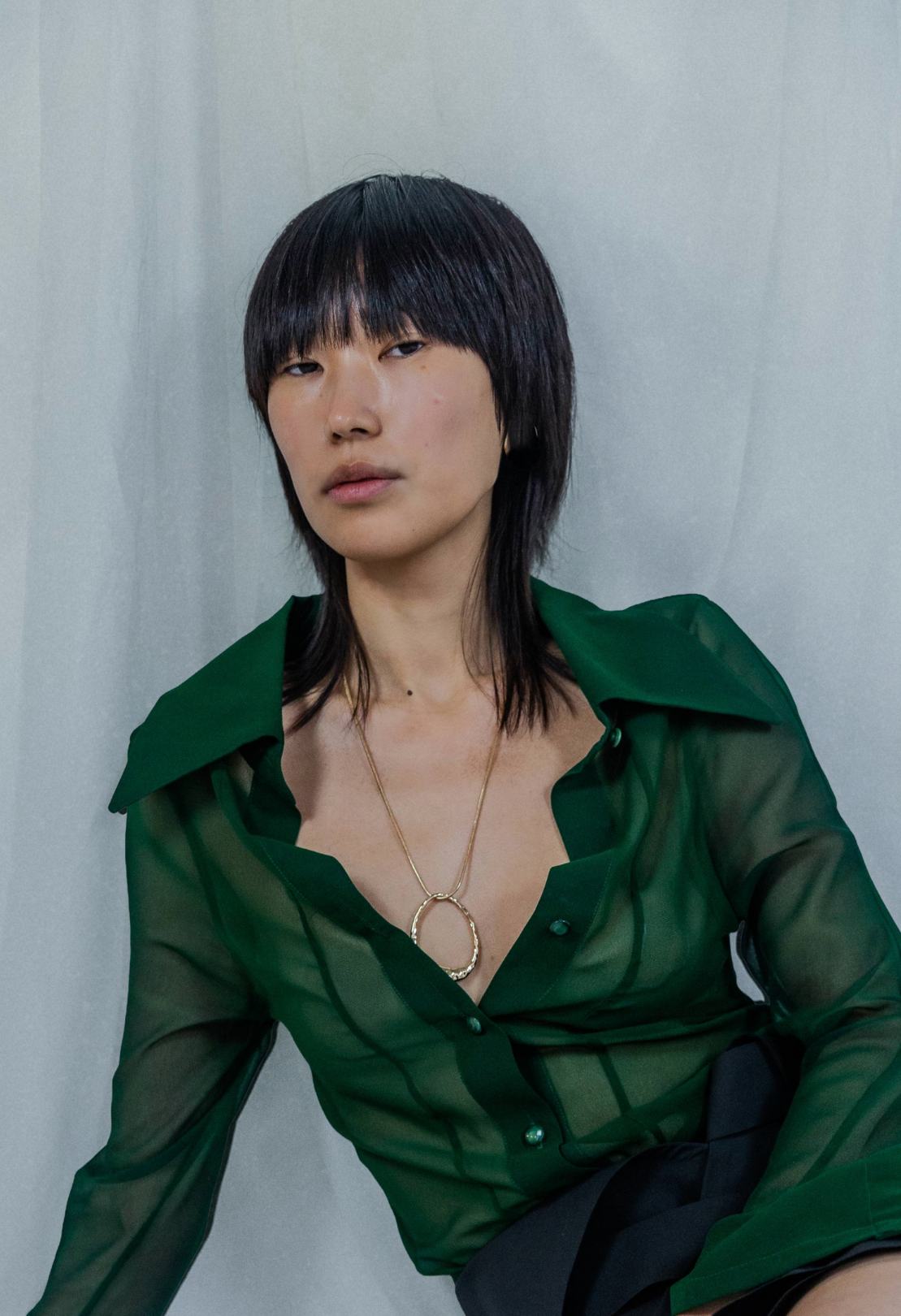 Person wearing a green blouse against a plain background